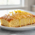 Saftiger Zitronenkuchen aus der Heißluftfritteuse auf einem Kuchenteller.