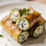 Leckere Zucchiniröllchen aus der Heißluftfritteuse auf einem Teller.